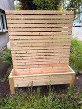 Cedar privacy planter box with attached full-height slat privacy screen, outdoors